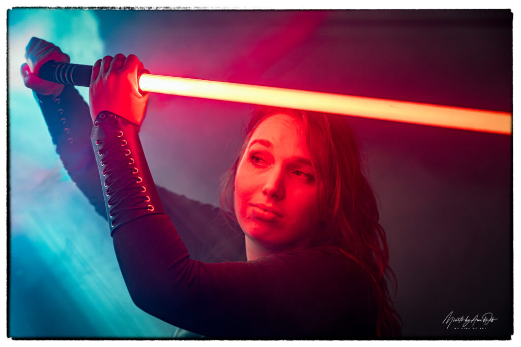 Frau mit rotem Lichtschwert und magischer Lichtaura â€“ intensiver Blick, umgeben von blauem Nebel.
