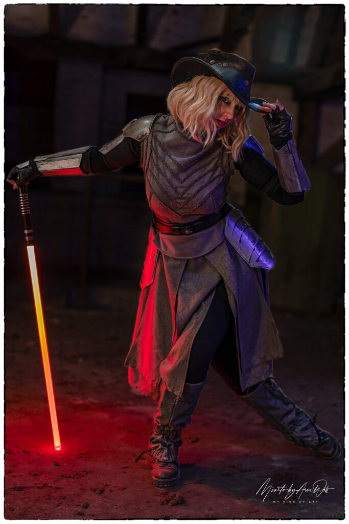 Cosplayerin mit rotem Lichtschwert in Sith-Optik â€“ kraftvolle Pose mit Rauch im Hintergrund.