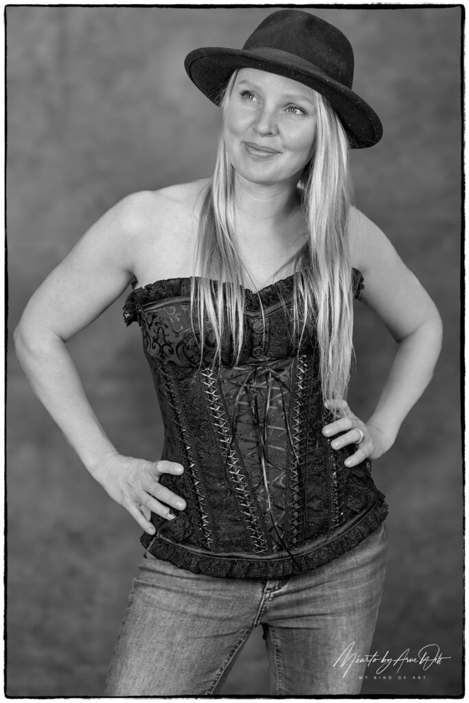 Frau in Jeans und Korsett, selbstbewusstes Lächeln, Schwarz-Weiß-Fotografie