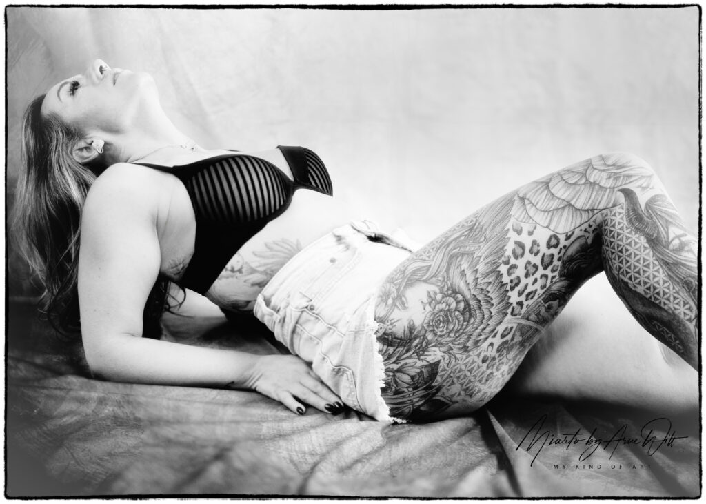 Boudoiraufnahme in Schwarzweiß: Frau liegt seitlich auf einem Bett, entspannt und elegant.